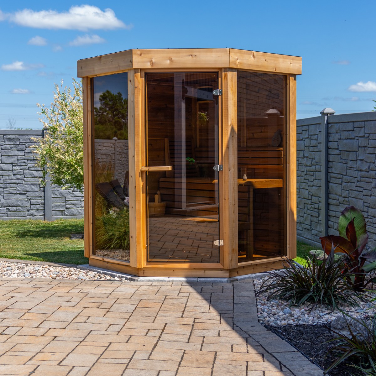 Trinity Pure Cube sauna with cedar framing, tempered glass panels and a flat roof on a paved patio.